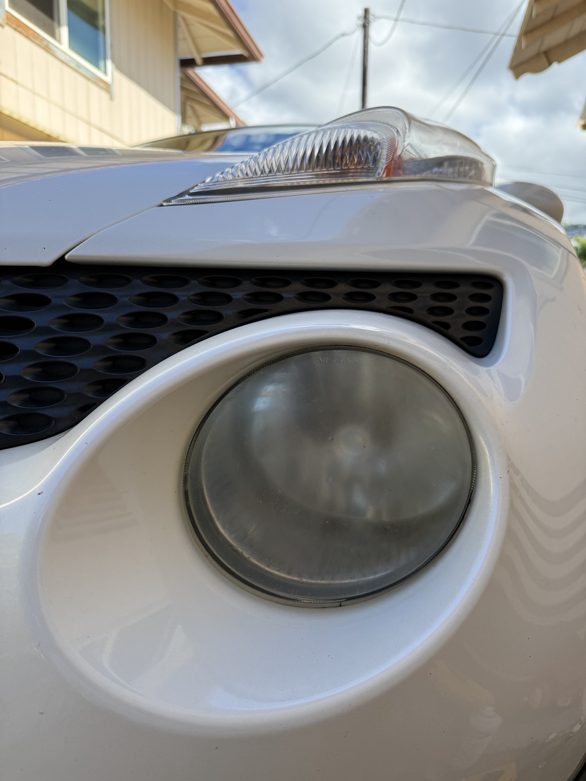 Cloudy round headlight on white Nissan before restoration
